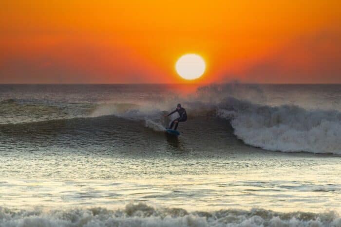 A surfer on the waves on Sotherndown Beach in Wales in the Autumn.