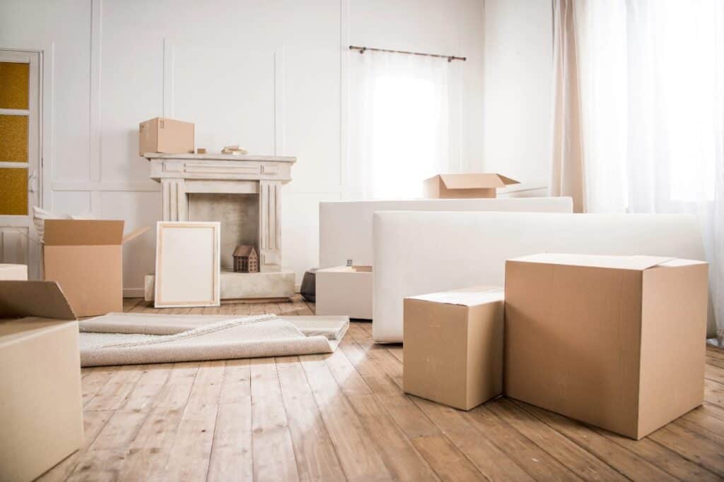 Cardboard moving boxes in a bright living room ready for moving house in the UK.