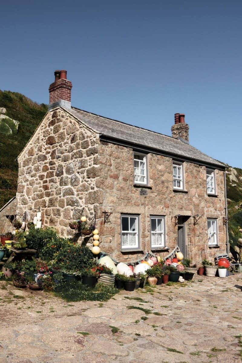 A charming stone house with a garden of potted plants and colourful decorations, representing the quest for finding the perfect family home.