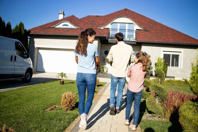Family walking towards a detached house during a viewing for a new family home.