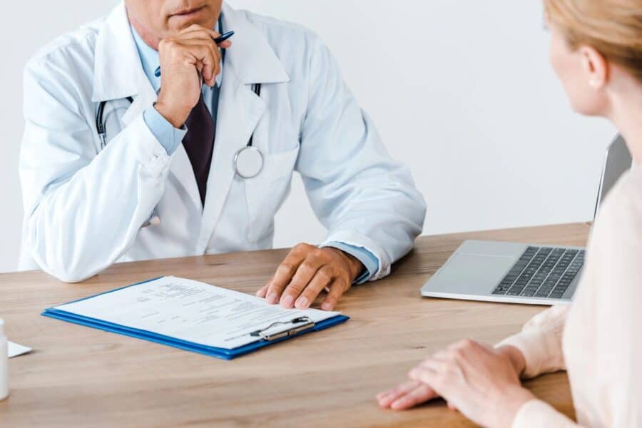 Doctor consulting with a patient, reviewing medical documents on a clipboard during an appointment.
