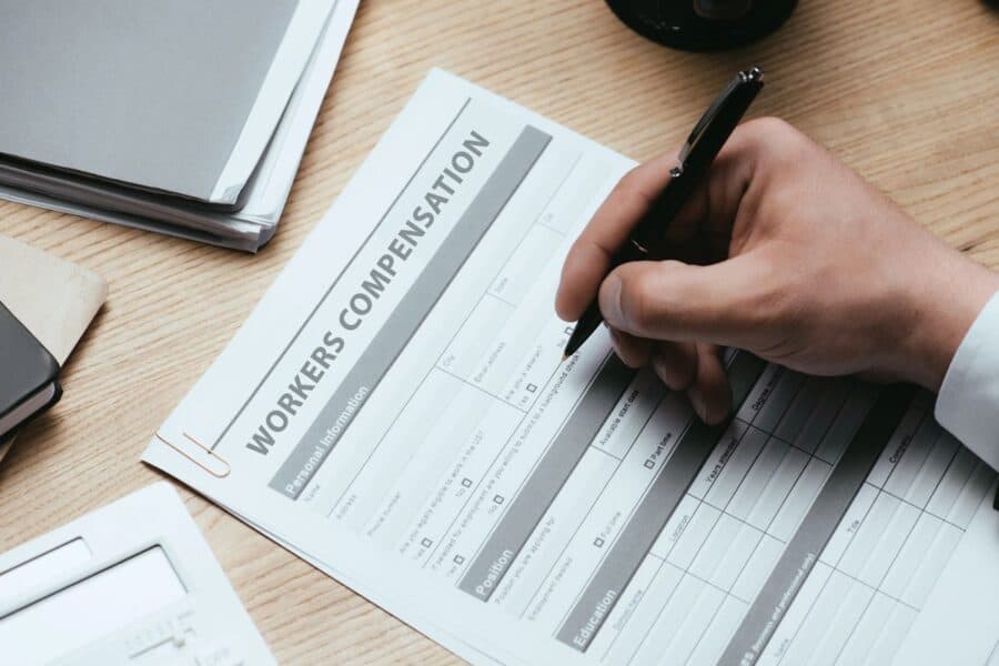 Close-up of a hand filling out a workers' compensation form, addressing rights after a workplace injury.