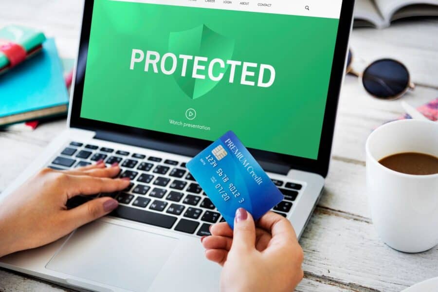 Person holding a credit card while looking at a laptop screen displaying the word 'PROTECTED,' symbolising cybersecurity in online transactions for ecommerce businesses.