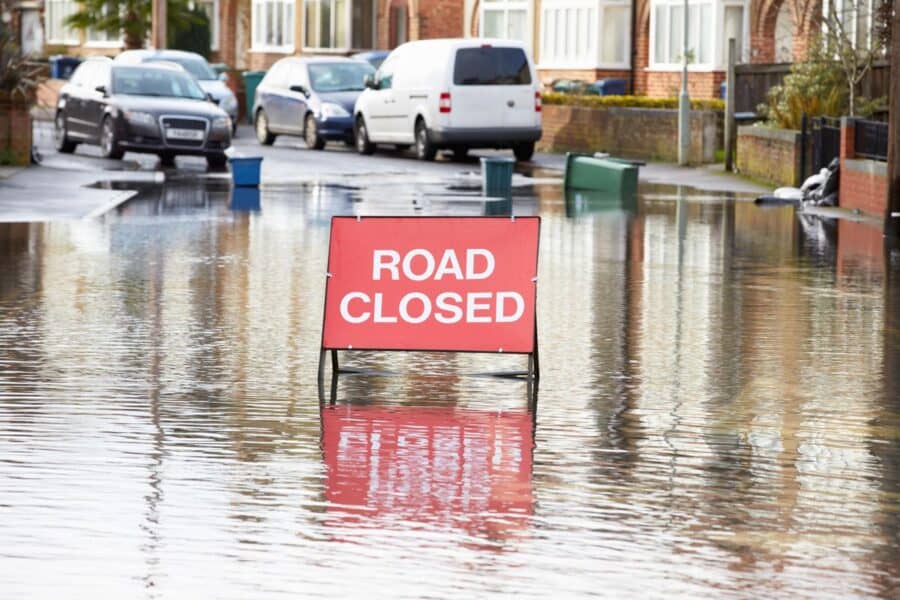 Flooded street with a “Road Closed” sign, illustrating the need to naturally protect your home from disaster risks.