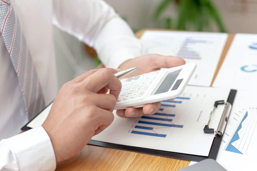 Businessperson using a calculator and reviewing financial charts, illustrating tasks related to accounting and financial analysis.