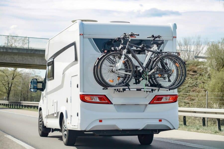 Rear view of a motorhome with bicycles mounted on the back, driving on a European highway, highlighting tips for exploring Europe by motorhome.