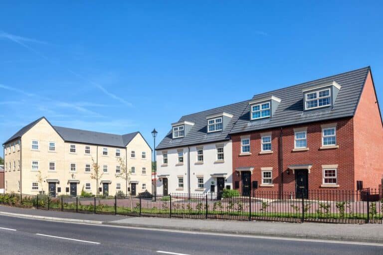 A row of modern new build homes in a rural location under a clear blue sky.