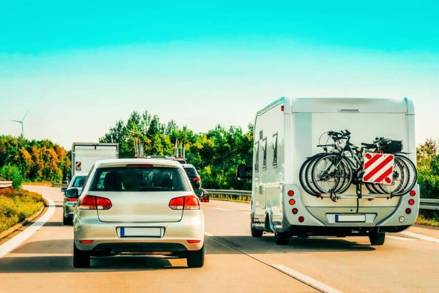 Motorhome with bicycles mounted on the rear driving on a sunny European highway alongside cars, capturing the essence of driving on roads in Europe by motorhome.