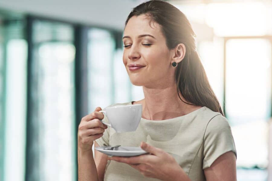 A woman enjoying a mindful moment with a cup of coffee, savoring the peaceful start to her morning routine.