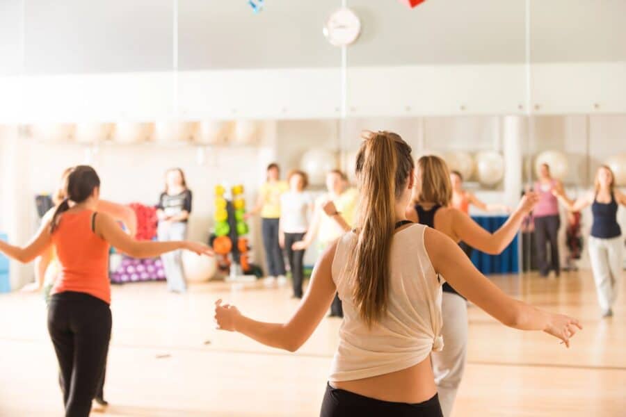 Group of women in a dance fitness class moving joyfully, showcasing how physical activity can naturally make you feel happier.