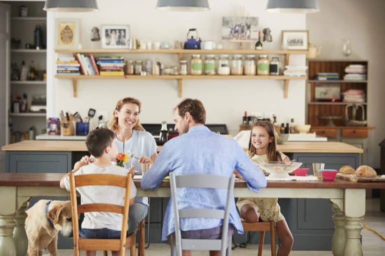 A family sitting together at a clean, organised dining table, enjoying a relaxed moment in the kitchen, symbolising preparation for the week ahead.