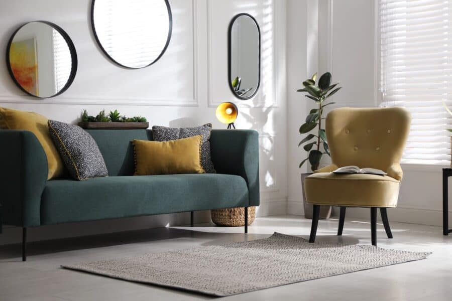 Modern living room with a grey sofa, mustard yellow chair, wooden coffee table, and stylish decor accents.