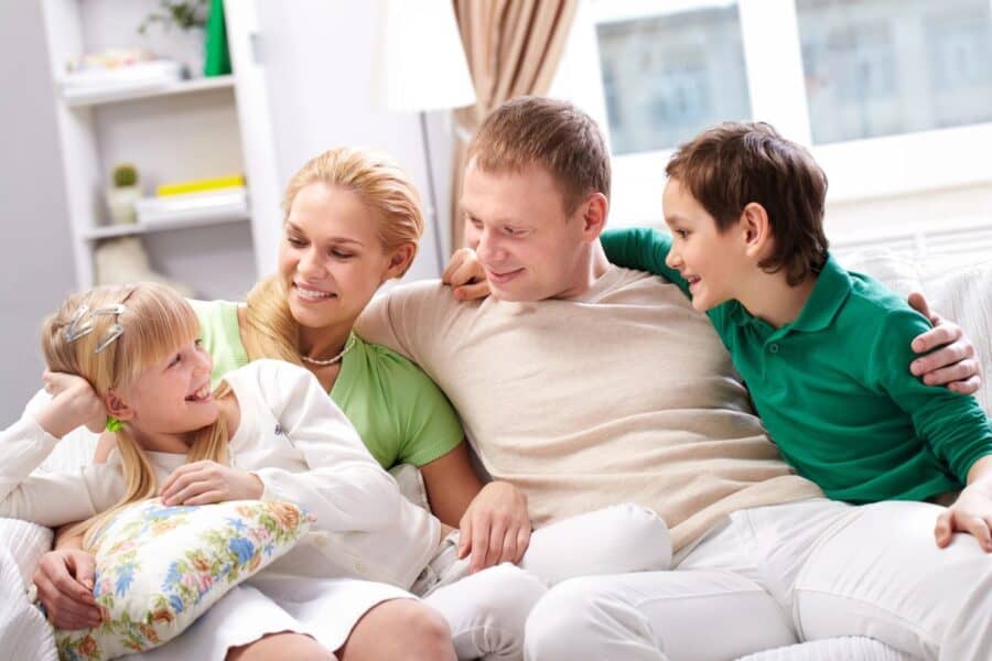 A family sitting together on a cosy sofa, smiling and enjoying quality time on a Sunday evening, symbolising relaxation and preparation for the week ahead.