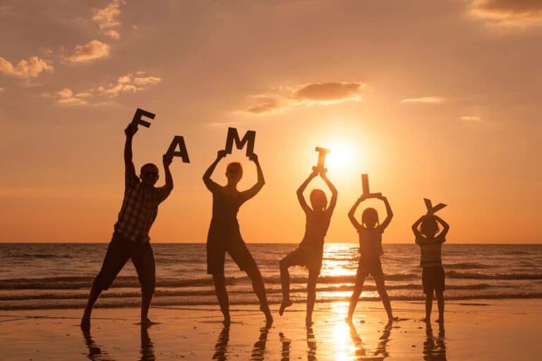 Silhouetted family on a beach at sunset, holding letters spelling 'FAMILY', symbolising deep family connections and togetherness.