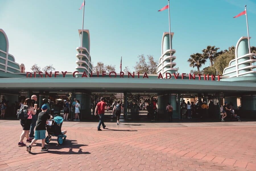 Entrance to Disney California Adventure with families and visitors walking toward the gates under a clear blue sky.