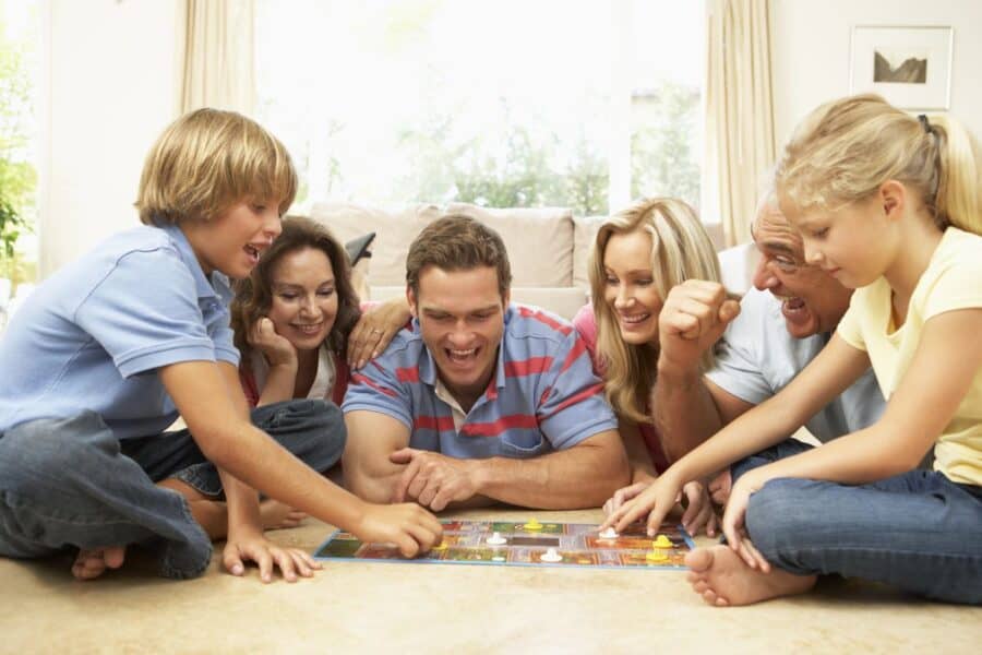 A happy multigenerational family playing a board game together, laughing and bonding through quality time, strengthening their family connections.
