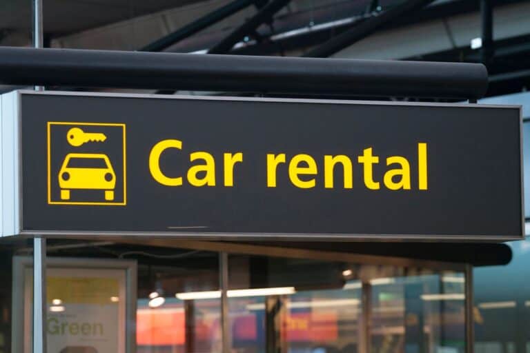 Bright yellow car rental sign at an airport, symbolizing the first step in following essential road trip car rental tips for a smooth journey.