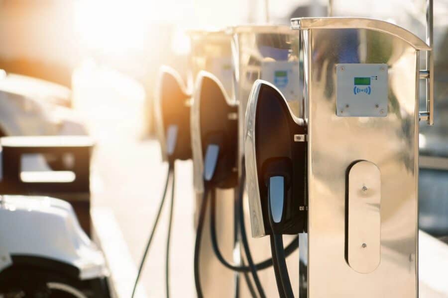 Electric vehicle charging stations with sunlight reflecting off the panels, representing eco-friendly options for road trips and essential car rental tips.