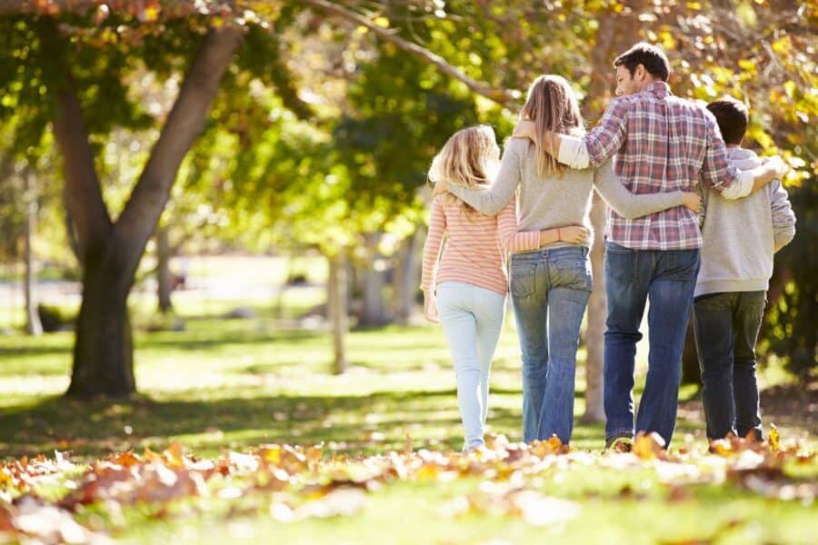 A family walking arm-in-arm through a scenic park, symbolising strong family relationships, emotional connection, and quality time together.