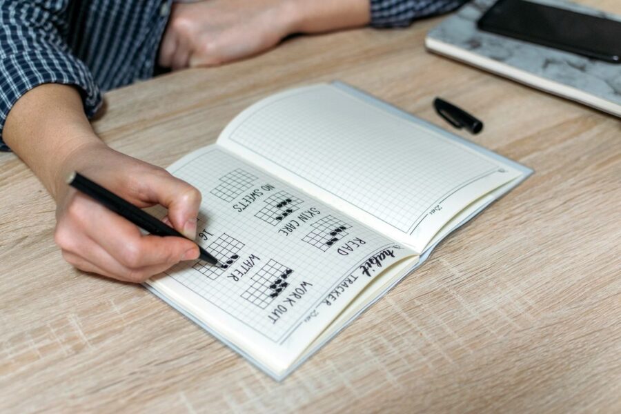 A close-up of a habit tracker journal being filled in, representing goal accountability, consistency, and staying on track with personal progress.