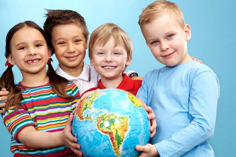 A group of smiling children holding a globe, symbolising unity, sustainability, and a commitment to protecting the planet for future generations.