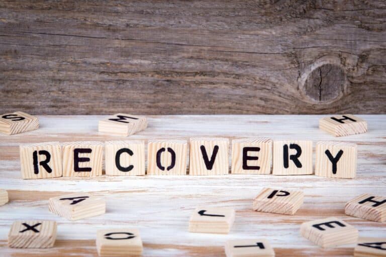 Wooden tiles spelling “recovery” symbolising building a healthy lifestyle after addiction.