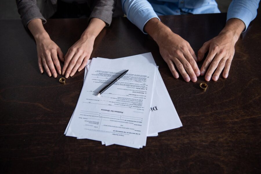 Man and woman sitting at a table with divorce papers and wedding rings.