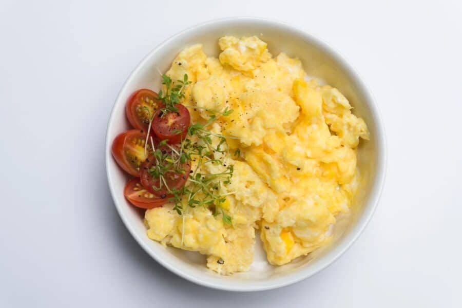 Scrambled eggs with cherry tomatoes and microgreens for a protein-rich breakfast to boost morning energy.
