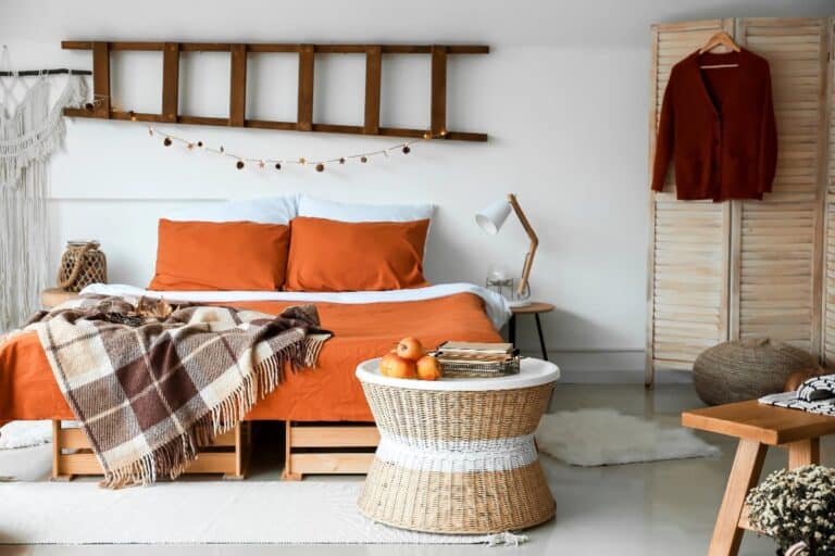 Bedroom reset for autumn with rust duvet, plaid throw, warm bedside lamp and natural textures in a calm neutral room.