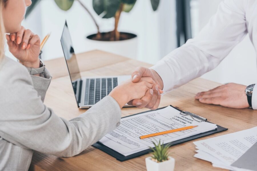 Business owner shaking hands with insurance advisor over paperwork, symbolising how to protect your small business with the right cover.