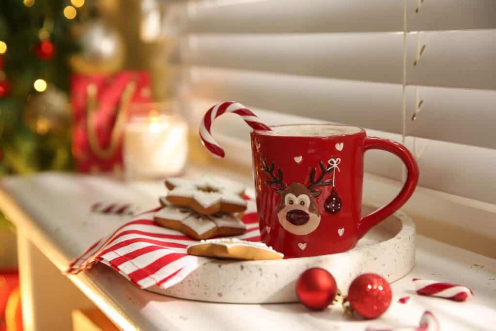 Festive mug of hot chocolate with candy cane and iced star biscuits — a cosy idea for Christmas Gifts for Chocolate Lovers