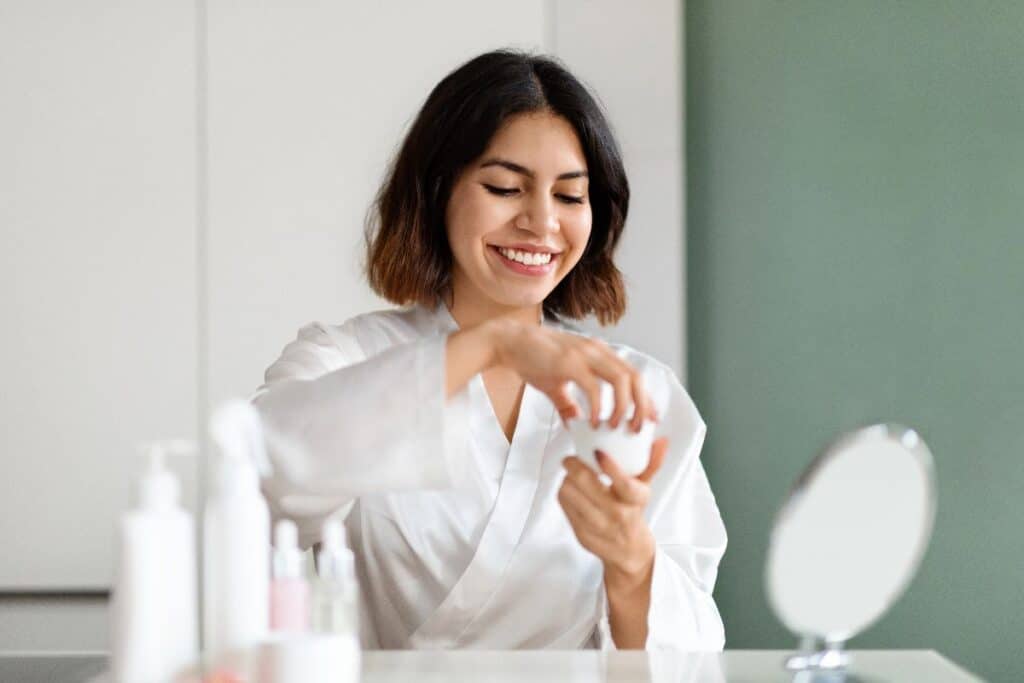 Woman applying face cream as part of a simple morning routine.