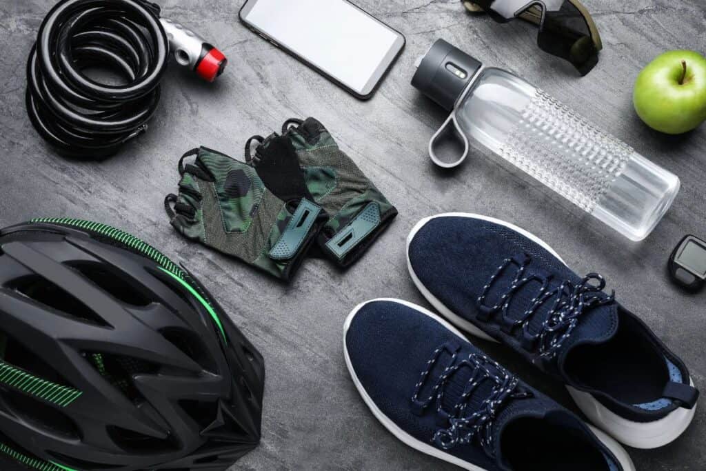 Cycling essentials laid out, including helmet, gloves, lock, bottle and trainers.