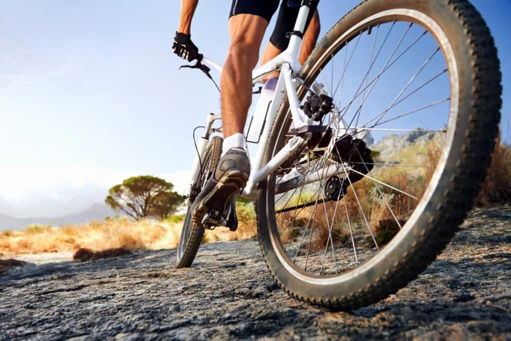 Man riding a white bike over rocky ground, demonstrating the best weekend bikes for men on tougher terrain.