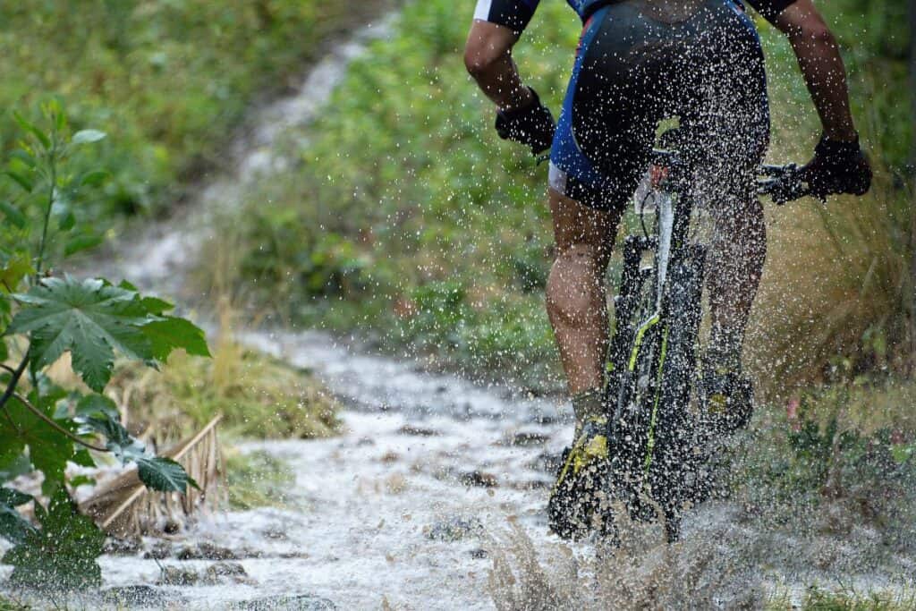 Man riding through a muddy trail on a mountain bike, showing the best weekend bikes for men that can handle off-road routes.