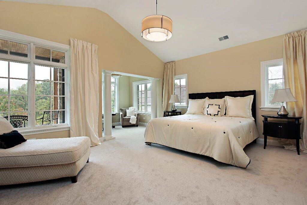 Home updates to transform your space — calm neutral bedroom with fresh carpet, layered lighting and airy curtains.