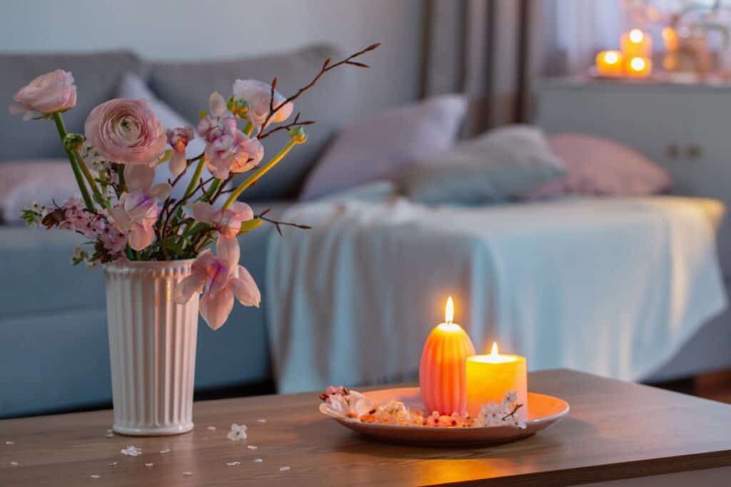 Soft evening bedroom scene with candles and flowers, creating a calm, cosy space to support a gentler winter mindset before sleep.