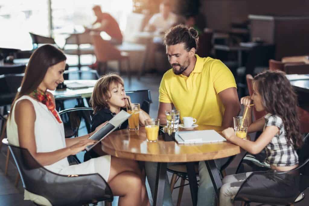 Family choosing from a menu at a casual restaurant, illustrating Restaurant Gift Vouchers UK as a family-friendly gift idea