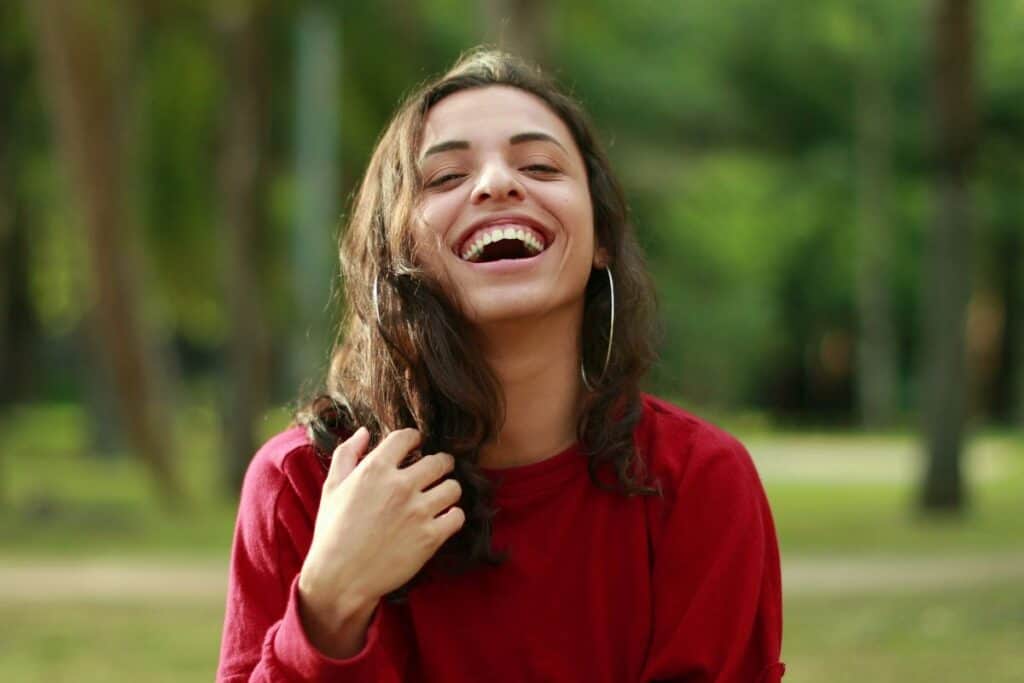 Smiling woman laughing outdoors, a simple joy boost moment.