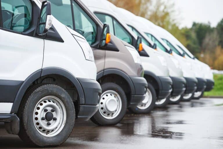 Row of company vans parked in a line, representing multi-vehicle insurance for UK small businesses.
