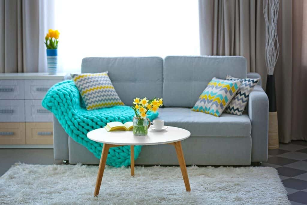 Spring living room decor with bright cushions, flowers and a cosy sofa
