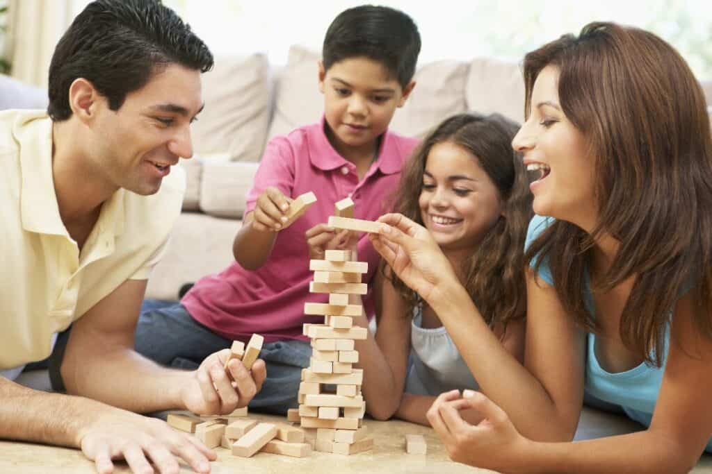 Family playing a wooden block game together at home as a simple family tradition.