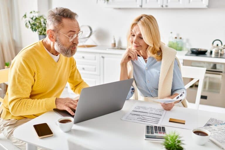 Couple taking control of their finances at home with bills, laptop and calculator