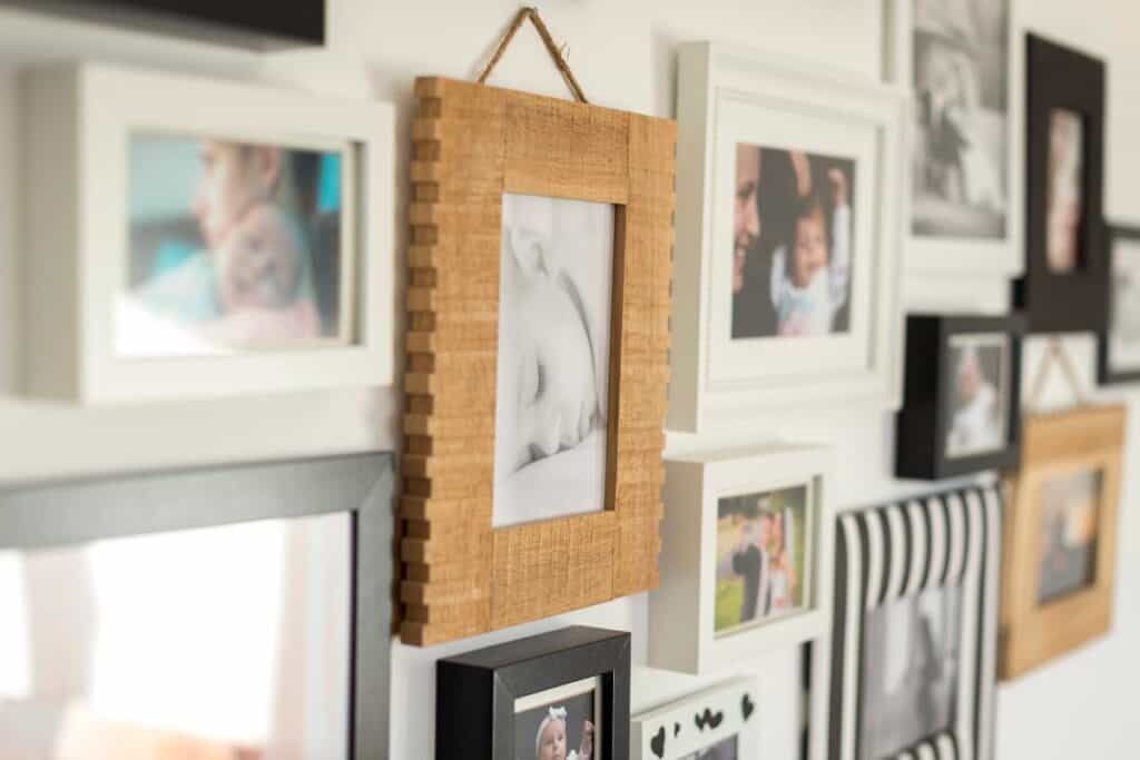 Family photo wall with framed pictures and mixed wooden and white frames on display.