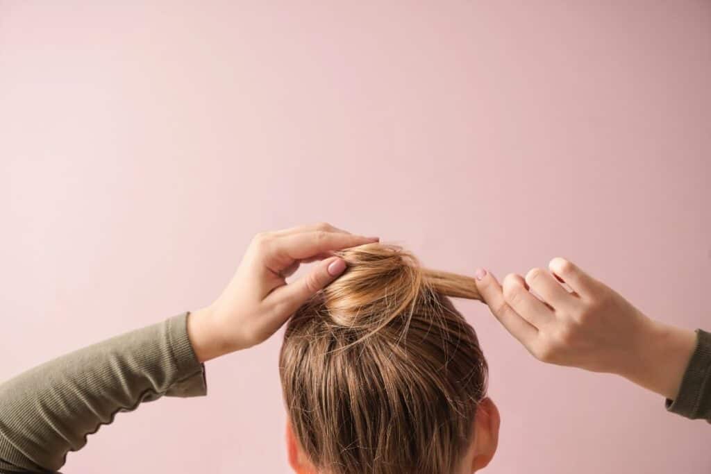 Woman creating a quick low bun hairstyle for a busy morning.