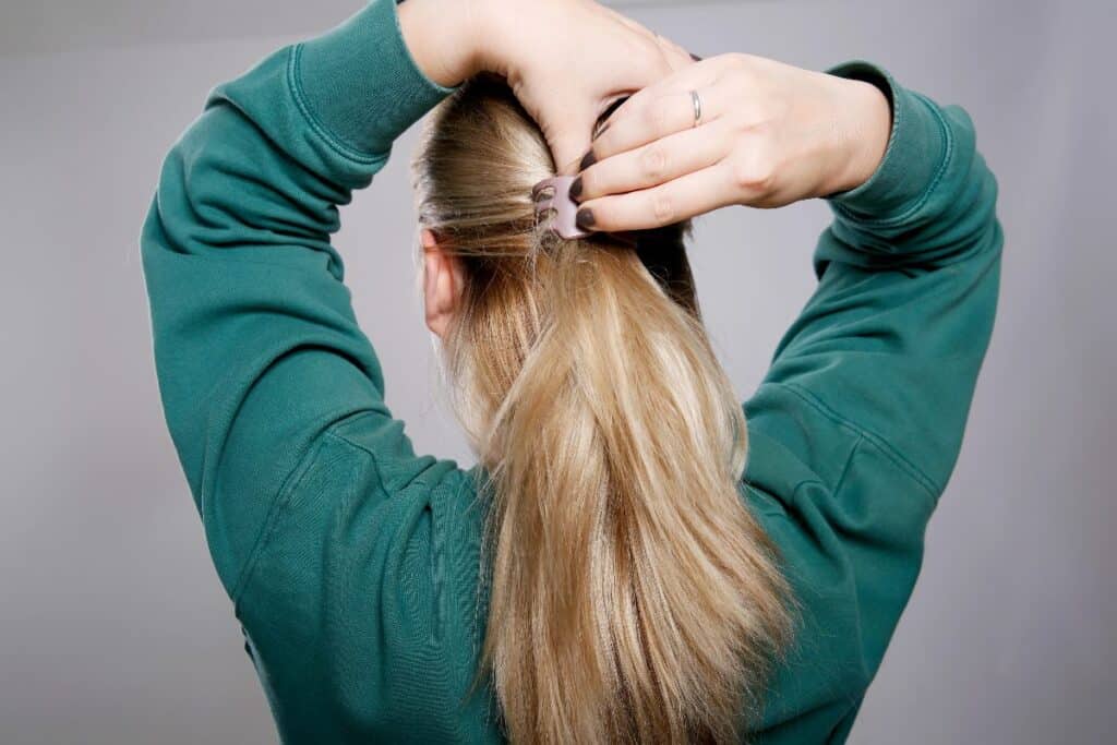 Woman clipping the top half of her hair back into a simple half-up hairstyle