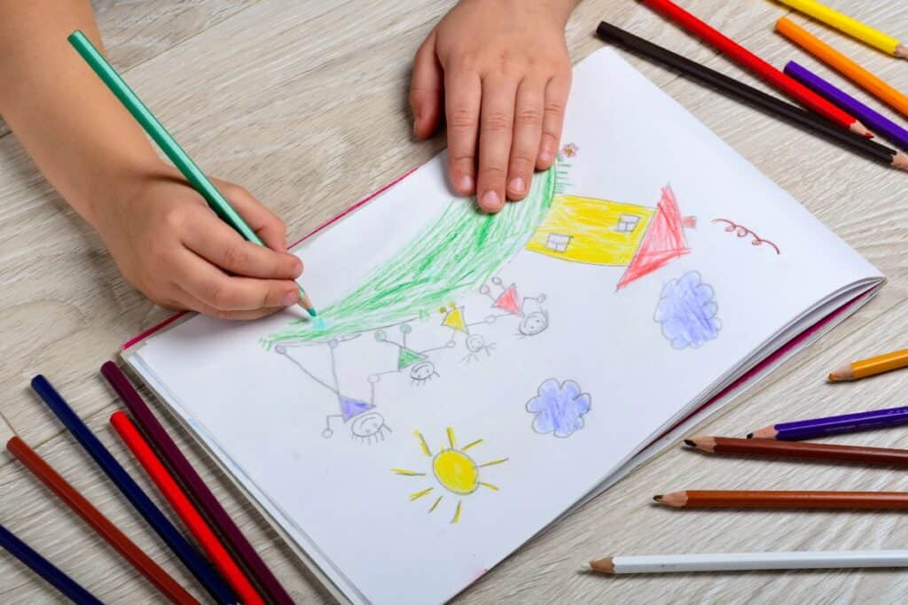 Child drawing a family picture with coloured pencils, showing how creative expression can help support a grieving child