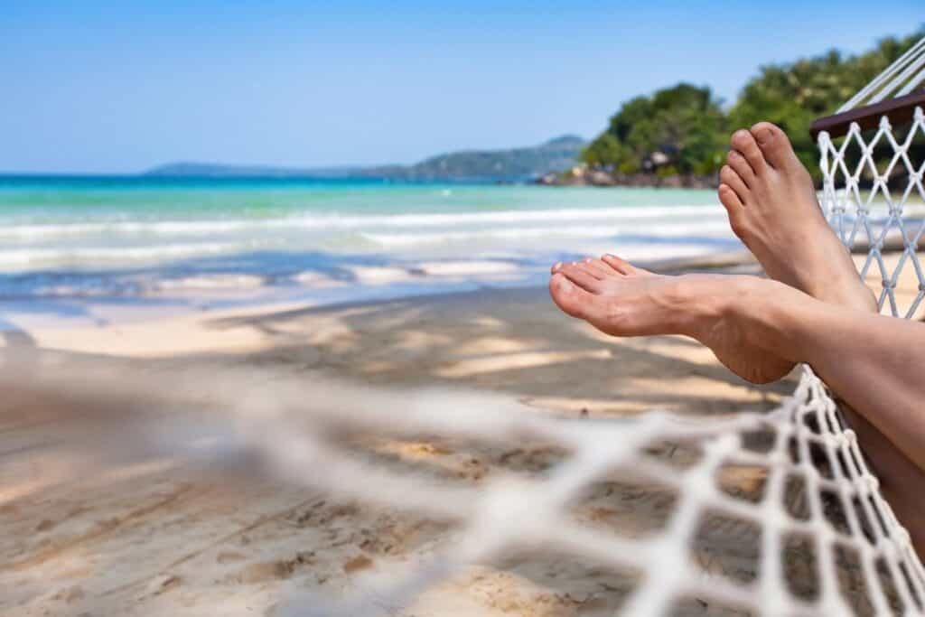 Person relaxing in a hammock by the beach, showing how holidays help you switch off and rest.