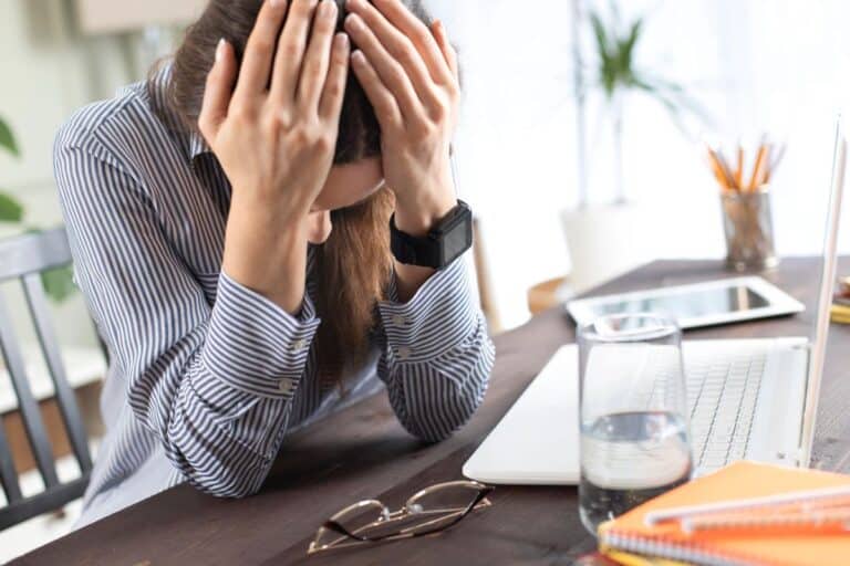 Woman feeling overwhelmed at a desk while trying to find clarity.