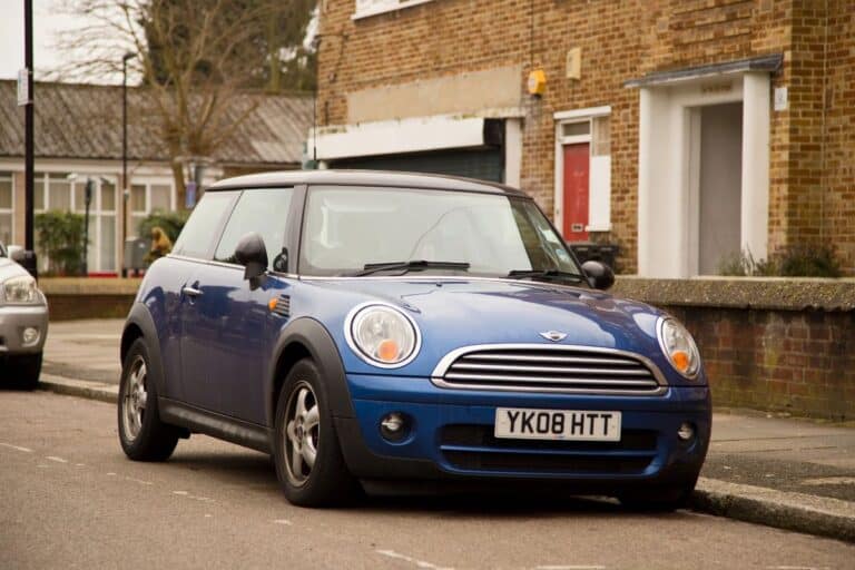 Blue car parked on a UK street with a front number plate visible.